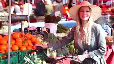 金发女孩骑着自行车站在市场上，微笑着
